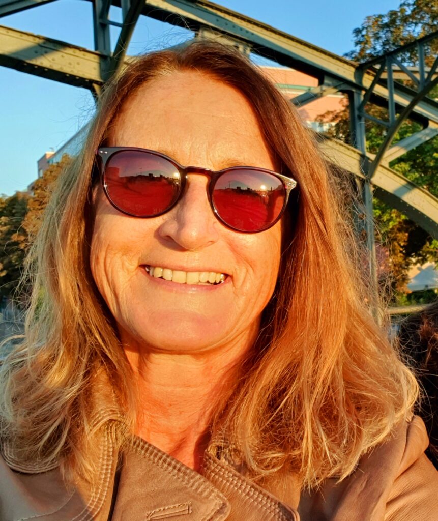 Katrina auf der Hackerbrücke in München lächelnd mit Sonnenbrille im warmen Licht der untergehenden Sonne