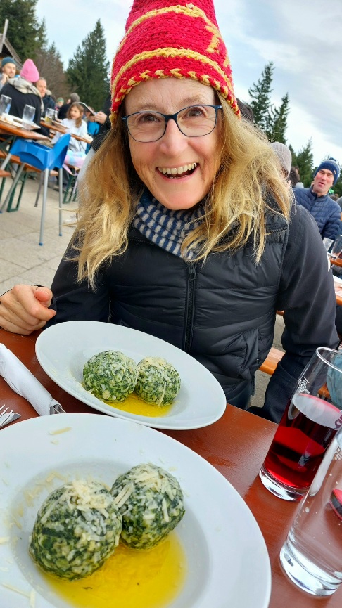 Kathrin Günther glücklich vor einem Teller Spinatknödel auf der Neureuth Alm in Bayern