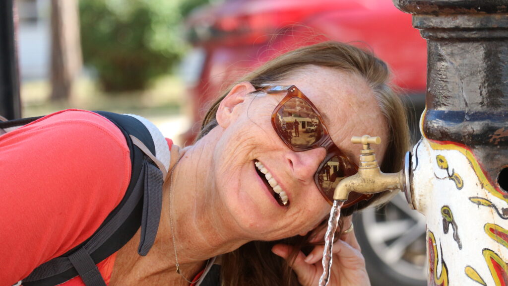 Kathrin Günther beim Triken aus einem Brunnen in Polignano al Mare in Apulien, Italien mit lächelndem Gesicht
