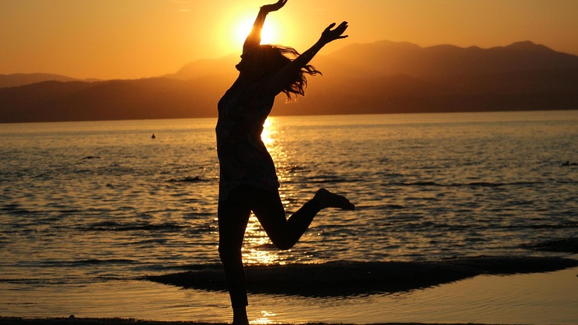 Kathrin Günther springt vor der untergehenden Sonne am Meer vor lauter Freude in die Höhe und reißt dabei die Arme hoch. Sie hüpft jeden Morgen 90 Sekunden für bessere Fitness und Freude